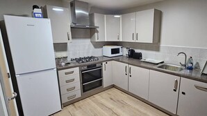 A modern kitchen with white cabinets, a built-in microwave, a gas stove, and a stainless steel refrigerator. - Cozy Corner For You ! (Newcastle-upon-Tyne)