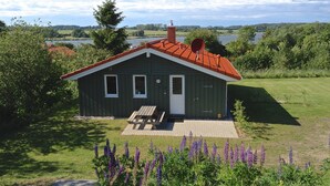 A small house with a red roof, a front door, and a small porch. - Holiday Home 'Skipper-Lodge West' with Sea View, Private Terrace and Wi-Fi (Kosel)