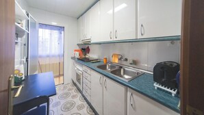 A compact kitchen with white cabinets, a blue countertop, and a black coffee maker.