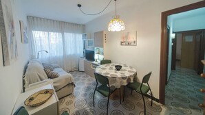 A compact living space with a dining area, a sofa, a small kitchenette, and a patterned floor.