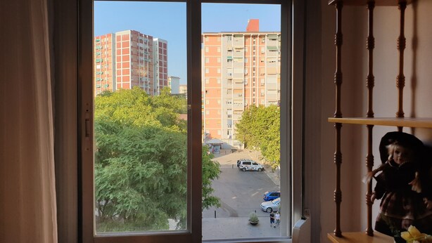 A view from a window overlooking a street with buildings and trees.