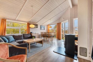 Una sala de estar moderna con un sofá, una mesa de comedor, sillas, una mesa de centro y una chimenea.