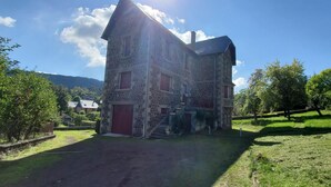 A stone building with a red door and a staircase leading to the entrance.