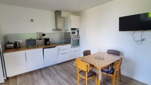 Una cocina moderna con armarios blancos, encimera de madera y una zona de comedor con mesa y sillas.
