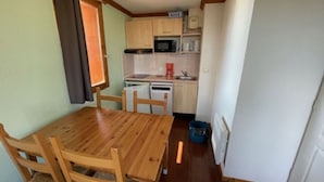 Une cuisine de taille réduite, dotée de meubles en bois, d’un four à micro-ondes et d’un évier.