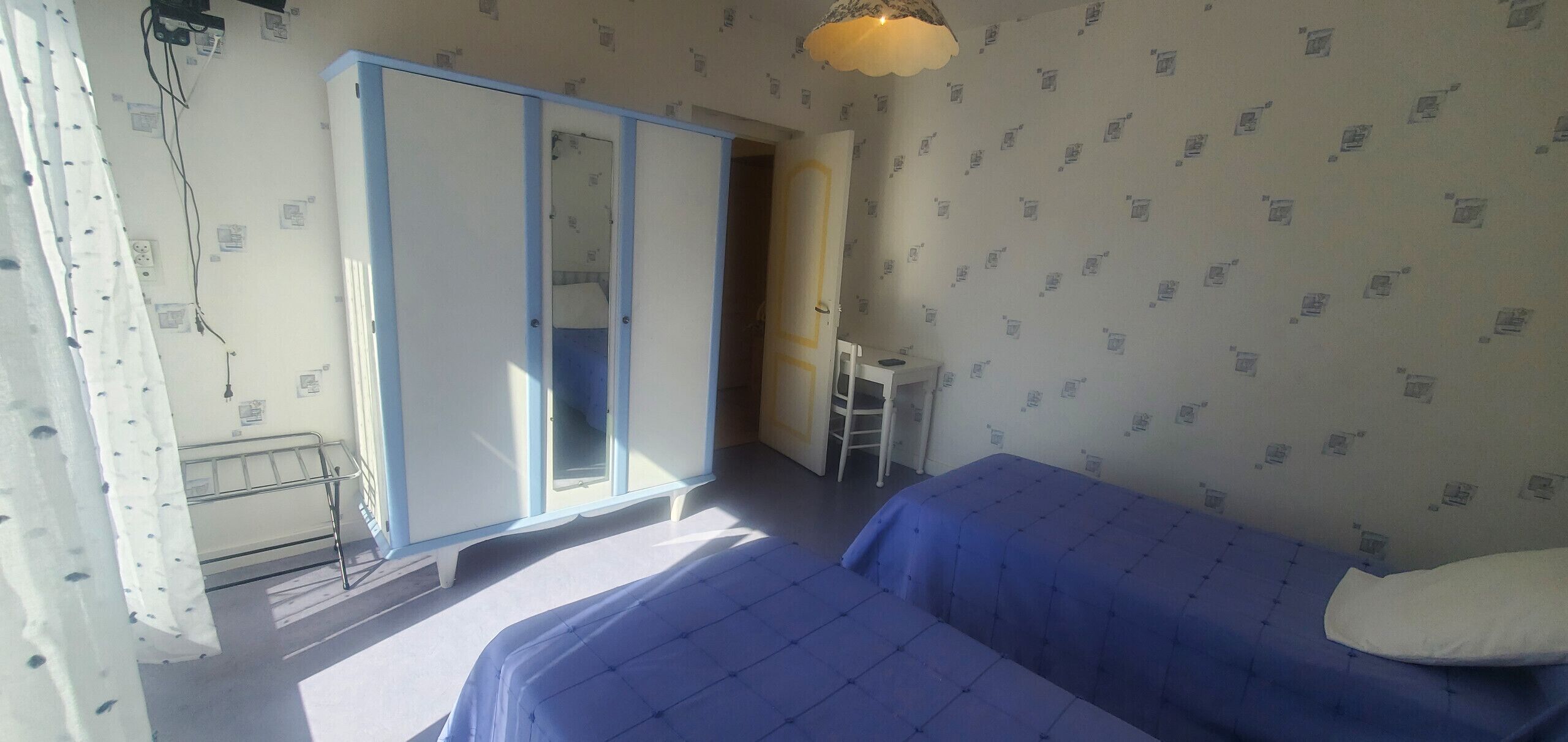 Un dormitorio con dos camas, un armario, un escritorio y una silla.