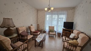 A living room with wooden furniture, a television, and a chandelier. - quietude (Murol)