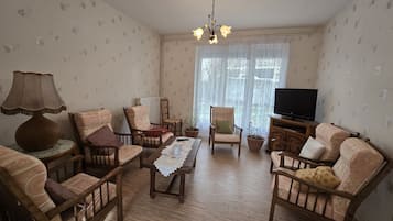 Un salon avec des meubles en bois, un téléviseur et un lustre.