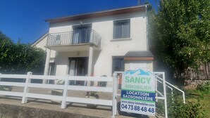 A two-story house with a balcony, a white fence, and a sign advertising real estate services. - quietude (Murol)