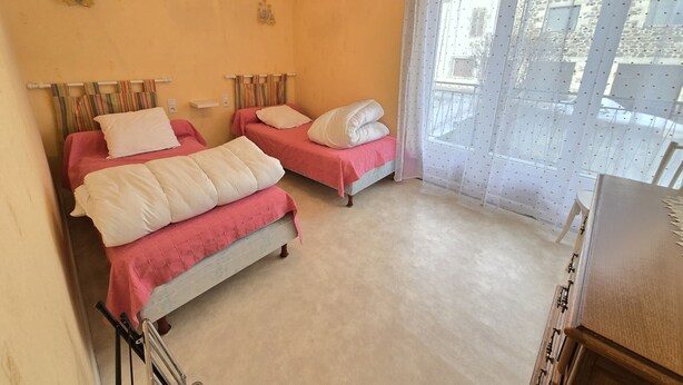 A bedroom with two beds, a window with a view, and a hanging light fixture. - quietude (Murol)