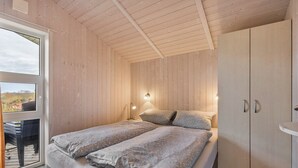 Ein Schlafzimmer mit Bett, Nachttischlampen, einem Kleiderschrank und einem großen Fenster.