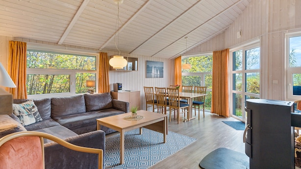 Ein gemütliches Wohnzimmer mit einer Couch, einem Esstisch, Stühlen und einem Kaminofen.