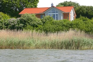 A house with a red roof, surrounded by tall grass and trees.