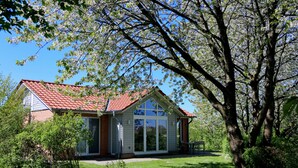 A house with a red roof, large windows, and a lawn.