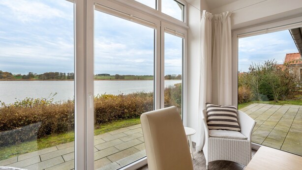 A room with large windows, a chair, and a table. - Holiday Home 'Schwanenuferhaus' with Sea View, Private Terrace and Wi-Fi (Kosel)
