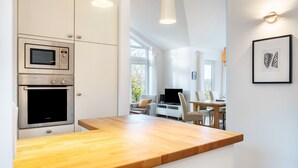 A modern kitchen with built-in appliances, a wooden countertop, and a dining area with a table and chairs. - Holiday Home 'Schwanenuferhaus' with Sea View, Private Terrace and Wi-Fi (Kosel)