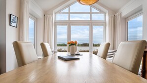A dining table with four chairs, a vase with flowers, and a framed picture on the wall. - Holiday Home 'Schwanenuferhaus' with Sea View, Private Terrace and Wi-Fi (Kosel)