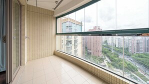 Un balcon doté d’une grande fenêtre donnant sur un paysage urbain.