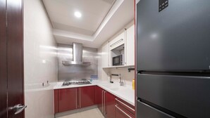 Une cuisine moderne dotée d’appareils électroménagers en acier inoxydable, de meubles de rangement rouges et de plans de travail blancs.