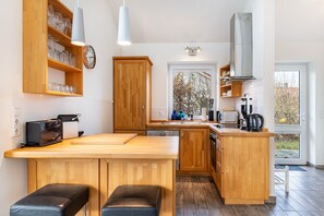A modern kitchen with wooden cabinets, a built-in island, and a window providing a view of the outdoors.