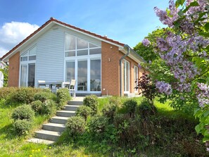 A house with a sloped roof, large windows, and a front porch with steps leading to a door.