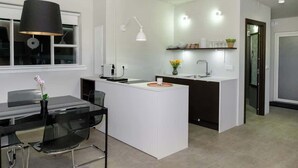A modern kitchen with a central island, white cabinetry, and a black pendant light.