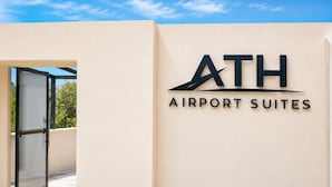 Une enseigne indiquant « ATH Airport Suites », avec un ciel dégagé en arrière-plan.