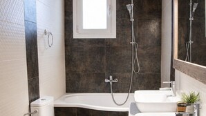 Une salle de bain moderne équipée d’une baignoire, de deux lavabos, de toilettes et d’une douche.