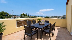 Un balcon avec une table et des chaises, un pot de fleurs et une vue sur la ville.