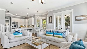 Un salón amplio con cocina moderna, comedor y una escalera que sube a otro nivel.