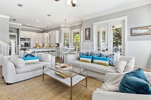A spacious living area with a modern kitchen, a dining area, and a staircase leading to another level. - NEW! Geauxing Coastal - Sleeps 10, 3 BR 3BA, Bikes, Community pool. PRIVATE BEACH ACCESS! (Seacrest)