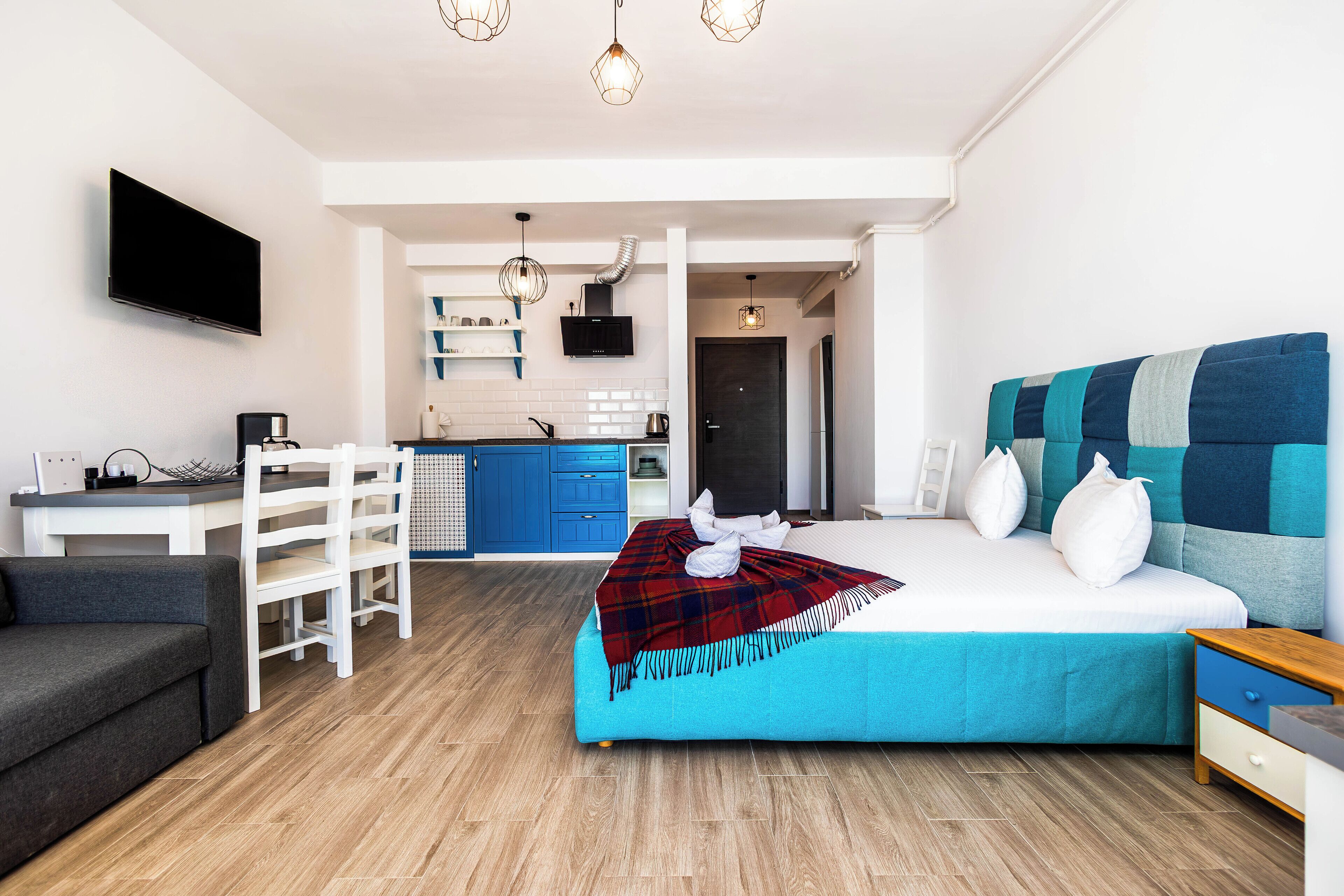A modern bedroom with a bed, a desk, and a TV.