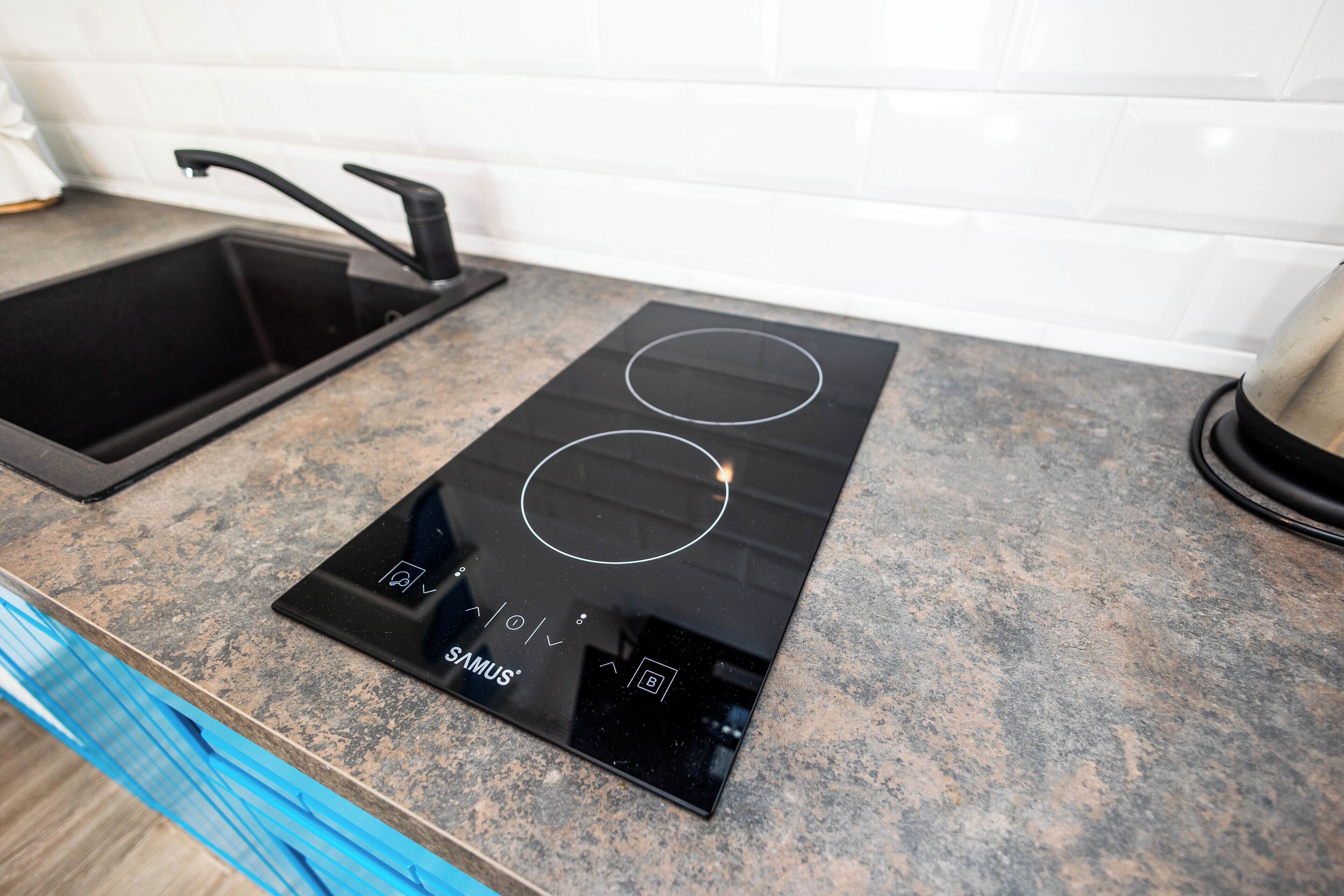 Une cuisine dotée d’une plaque de cuisson à induction noire et d’un évier en acier inoxydable.
