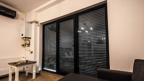 A modern room with a radiator, a table, a sofa, and large windows with blinds. - Casa del Mar 3 (Navodari)