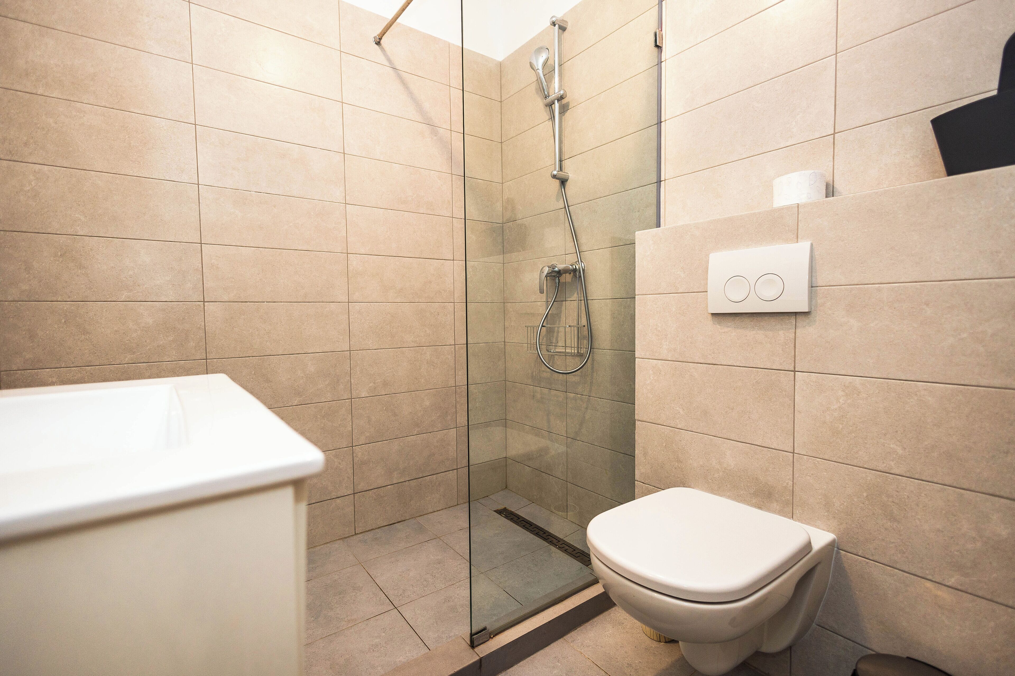 Une salle de bain moderne avec une douche à parois de verre, des toilettes blanches et un panneau de commande mural.