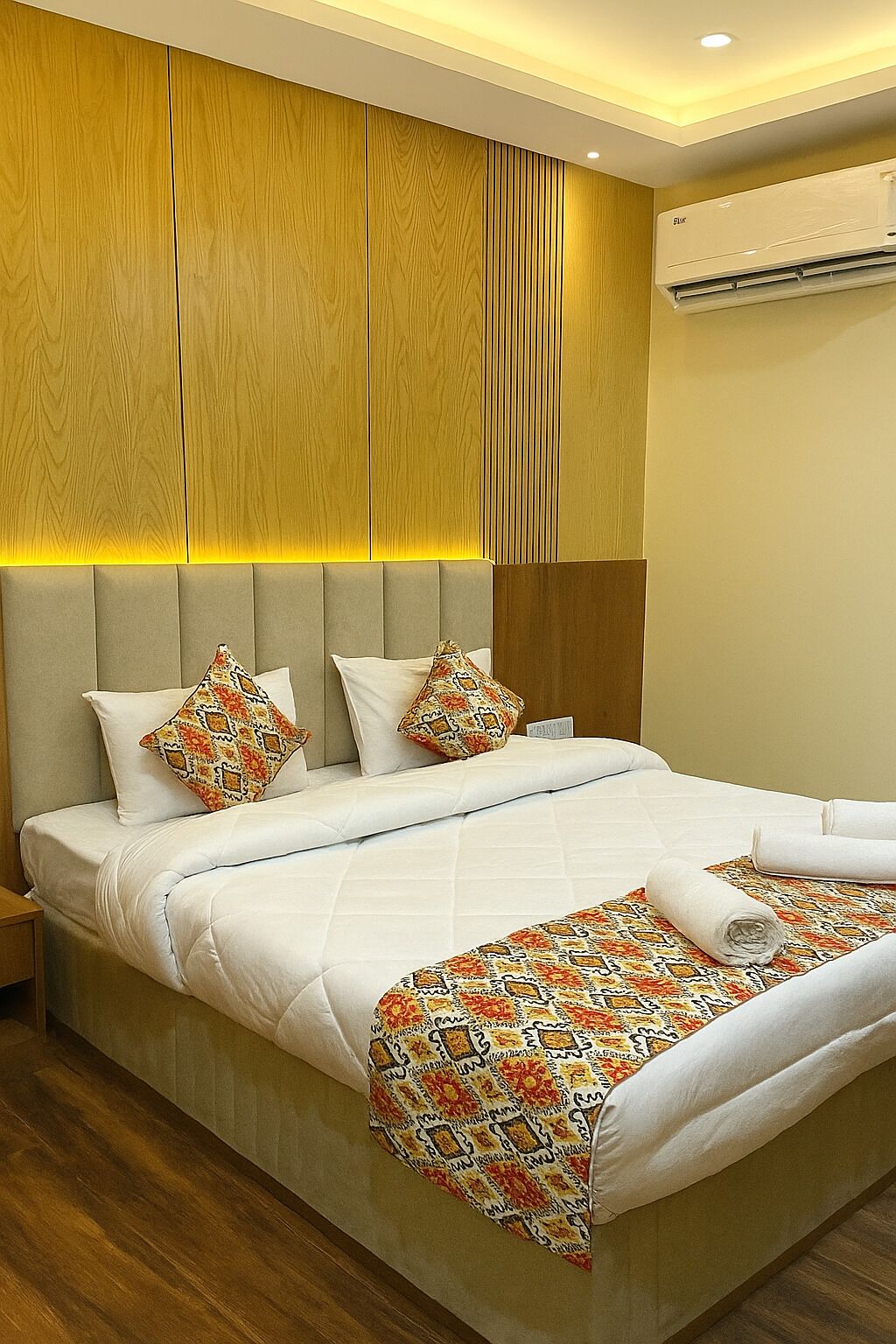 Een hotelkamer met een groot bed, houten lambrisering aan de wanden en een airconditioner.