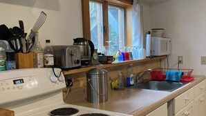 A kitchen with a white stove, a microwave, and various kitchen items on the counter. - Charming garden apartment with AC near Lake Fairlee, WFi. (Fairlee)