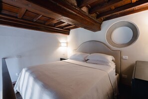 Un lit avec une tête de lit en bois, un miroir rond accroché au mur et une lampe de chevet.