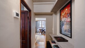 A hallway with a wooden door, a white thermostat, a dining area in the background, and a framed artwork on the wall. - Da Carlo Apartment in Pontevecchio (Firenze)