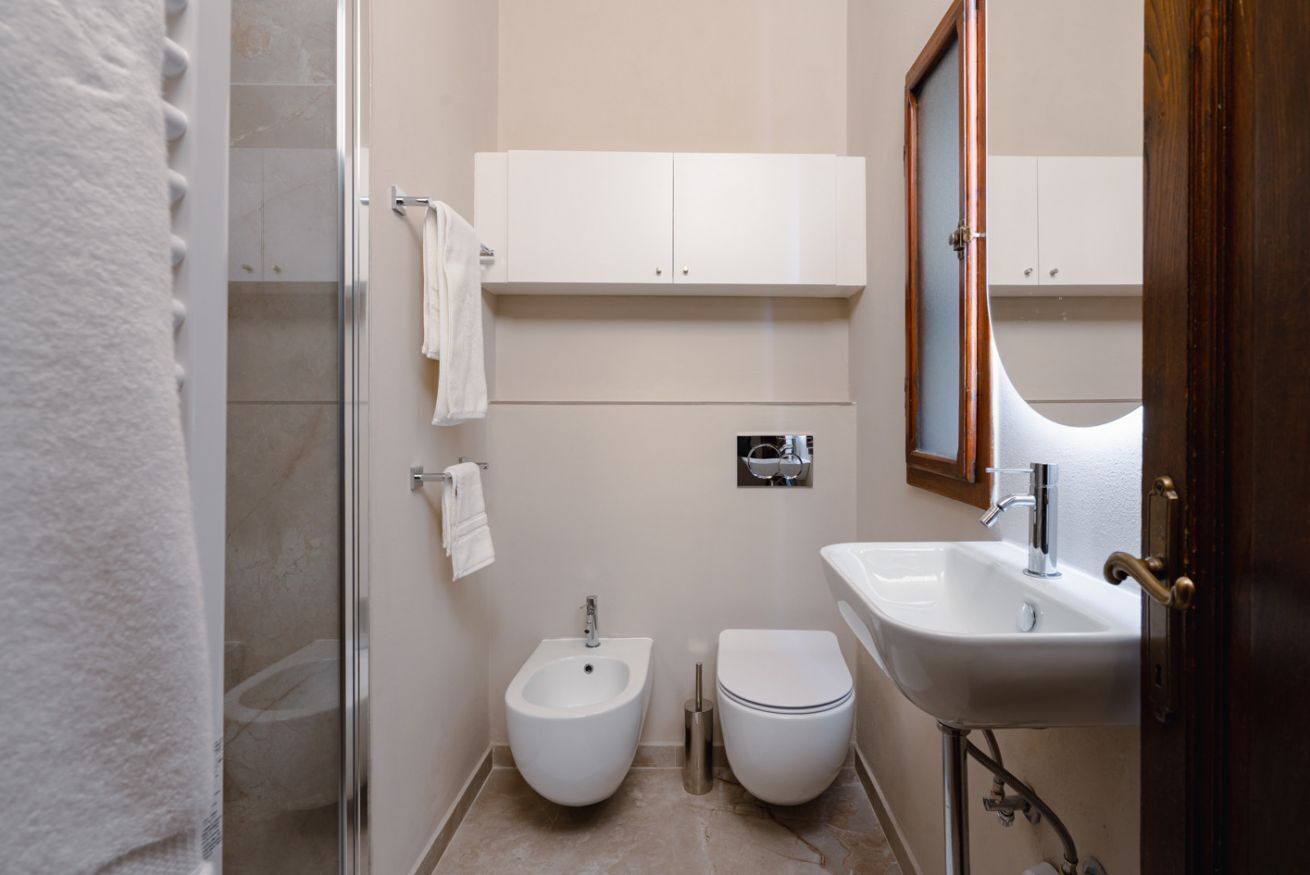 A bathroom with a bidet, toilet, sink, and a mirror.