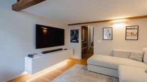 A modern living room with a flat-screen TV, white sofa, and a staircase leading to another level. - Da Carlo Apartment in Pontevecchio (Firenze)