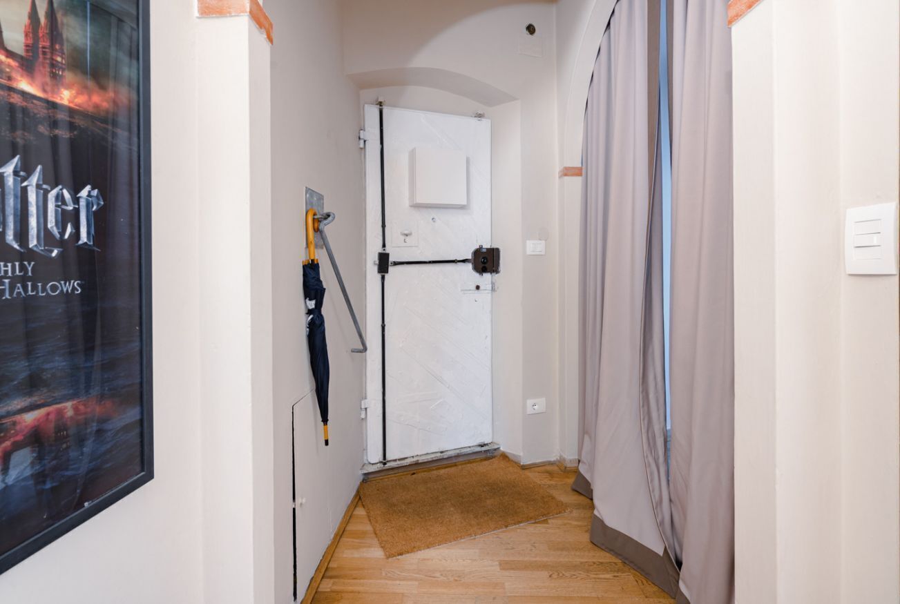 A narrow hallway with a door, a poster, and a doormat.