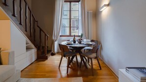 A dining area with a wooden table, chairs, and a view of the outside through a window. - Da Carlo Apartment in Pontevecchio (Firenze)