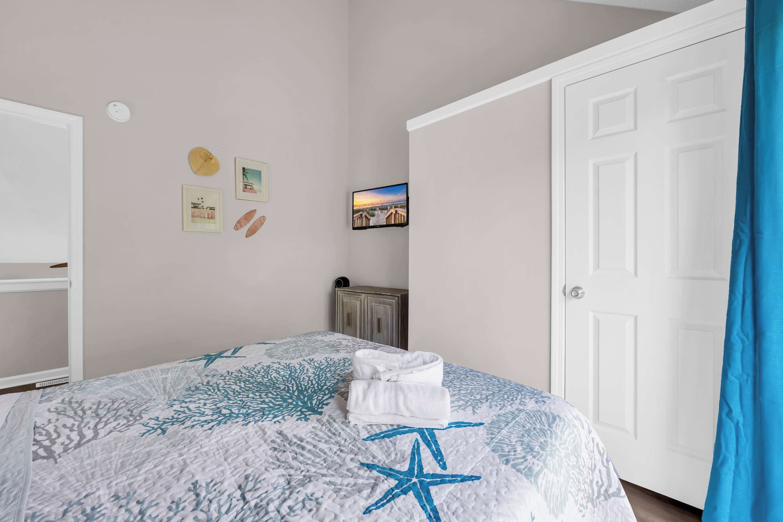 A bedroom with a bed, a white door, and a blue curtain.