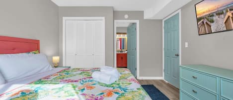 A bedroom with a bed, a dresser, and a bathroom visible through an open door.