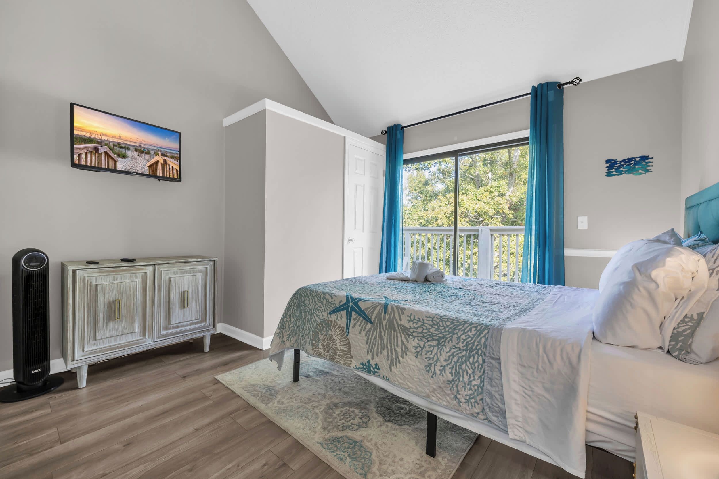 A bedroom with a bed, a radiator, a TV, and a window with curtains.
