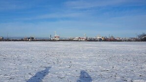 Et snøklædt landskab med industrielle bygninger og en frossen sø.