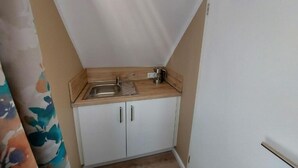 Et lille tekøkken med vask, kaffemaskine og skab.
