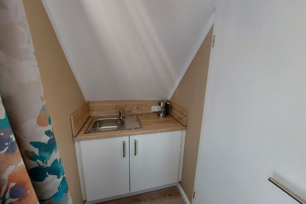 Een kleine kitchenette met een spoelbak, een koffiezetapparaat en een kastje.