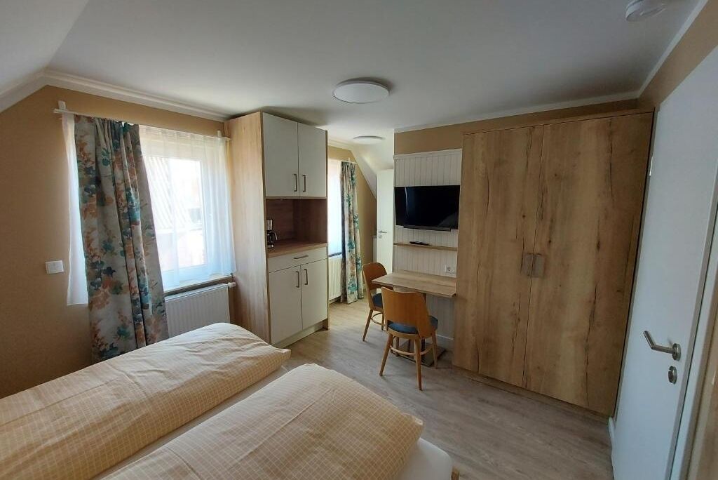 Een slaapkamer met twee bedden, een bureau, een stoel, een televisie en een kledingkast.